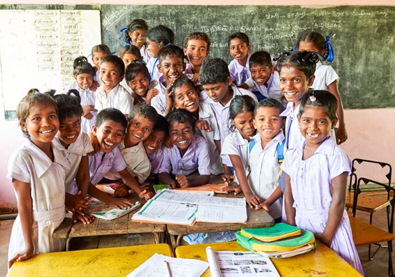 A group of smiling school kids gathered around the table