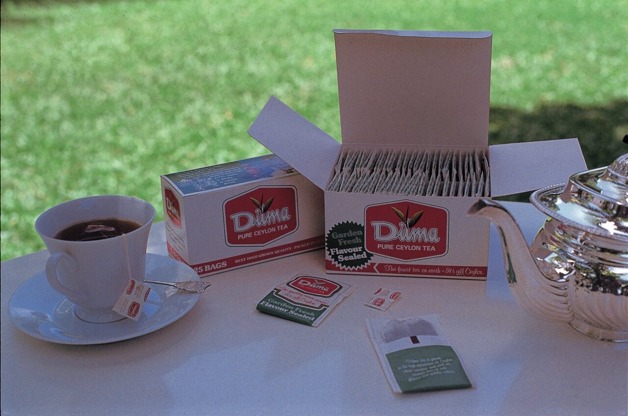 Open Dilma pack with tea bags cup of tea and teapot on the table