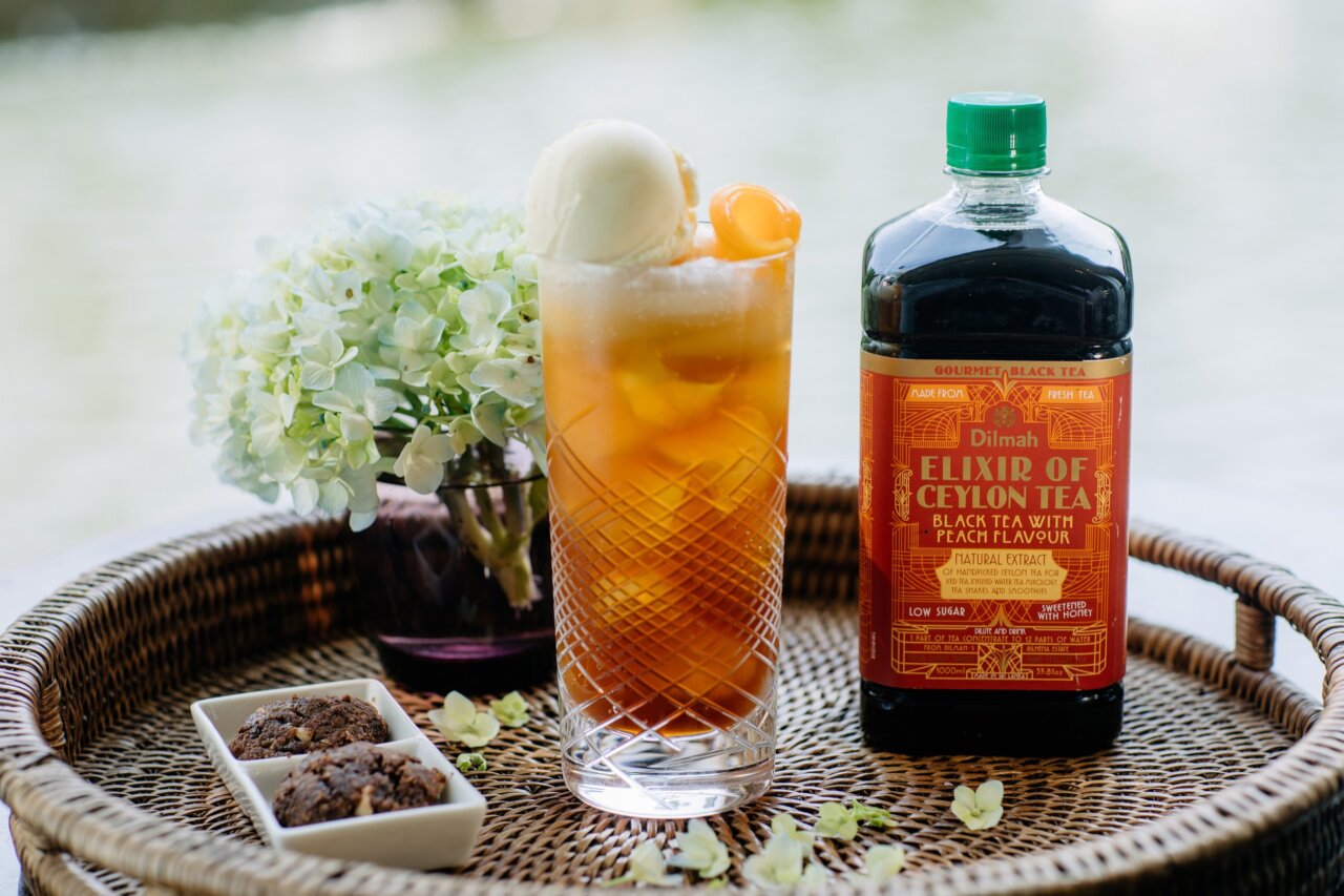 Dilmah Elixir of Ceylon Tea bottle and a glass with tea cocktail on a tray